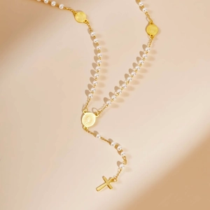 Dettaglio della collana rosario dorata con perle, medaglie religiose e pendente a croce