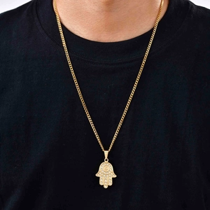 Primo piano dettagliato di una collana con ciondolo Mano di Fatima dorata con pietre