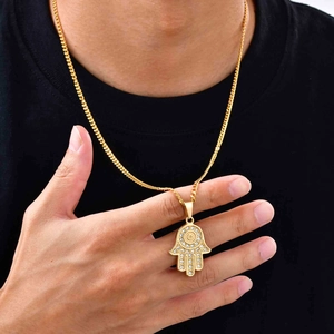 Collana con mano di Fatima dorata e zirconi indossata su sfondo di maglietta nera