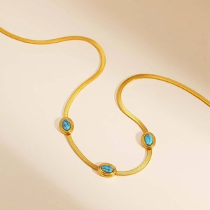 Dettaglio della collana a catena a serpente dorata con tre pietre turchesi ovali