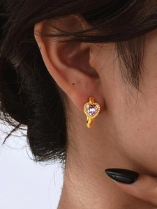Detailopname van gouden oorring met roze hart-zirkonia en kralenrand op model