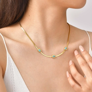 Dettaglio della collana a catena serpente dorata con tre pietre turchesi su modella