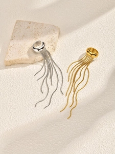 Macro shot of gold and silver ear cuffs with delicate tassel chains on stone surface