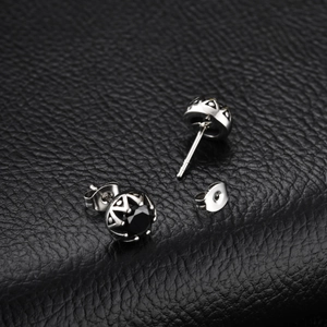Détail de boucles d'oreilles en acier titane avec couronne de zircon bleu et gravures