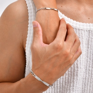 Close-up of a couple wearing silver Mobius twisted bar bracelets with flat curb chains