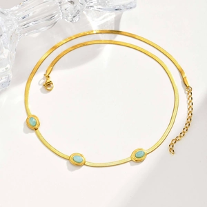 Dettaglio della collana a catena serpente dorata con tre turchesi ovali e chiusura a moschettone