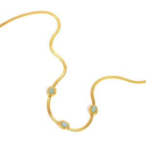 Dettaglio della collana a catena serpente dorata con tre pietre ovali turchesi su sfondo bianco