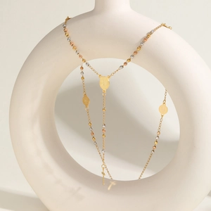 Dettaglio collana con perle tricolore, medaglie religiose e croce su ceramica bianca