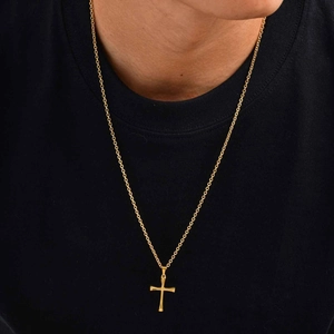 Primer plano de un colgante de cruz de acero dorado en una cadena trenzada para mujer