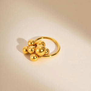 Bold golden stainless steel cluster ring with polished spheres on minimalist background