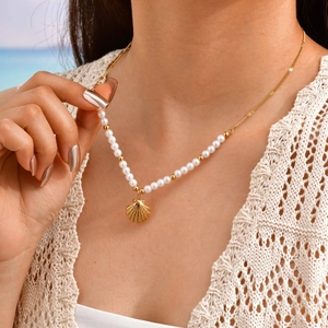 Detail of shell pendant and pearl necklace worn by a model in soft coastal light