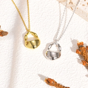 Macro view of minimalist irregular gold and silver pendants on a textured stone surface