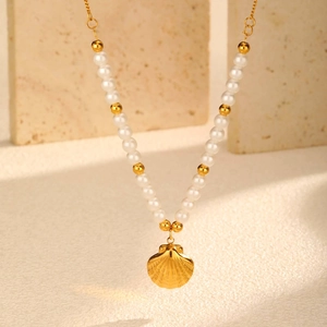 Macro shot of gold seashell pendant with white pearls on a textured stone background