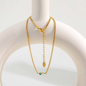 Dettaglio della collana a catena cubana dorata con zirconi blu e bianchi incastonati