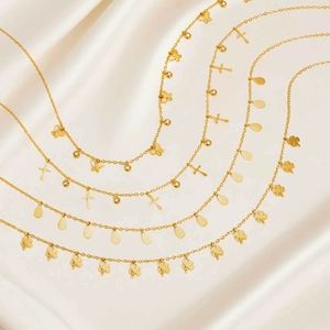 Detail von vier Goldketten mit Schmetterling-, Kreuz-, Tropfen- und Kleeblattanhängern