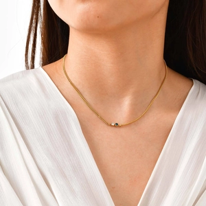 Dettaglio di una collana a catena cubana dorata con pendenti in zircone bianco e blu scuro