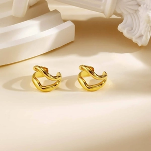 Bagues d'oreille ondulées minimalistes en acier inoxydable doré brillant sur podium blanc