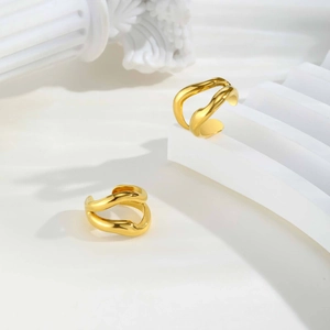 Vue macro des boucles d'oreilles vagues en or 18K avec texture polie fluide