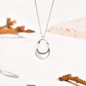 Close-up of minimalist 18K gold irregular hollow pendant with a polished mirror finish