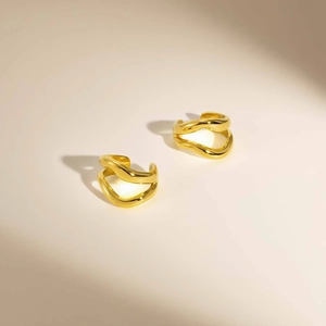 Vue détaillée des bagues d'oreille dorées à double vague avec une finition polie miroir