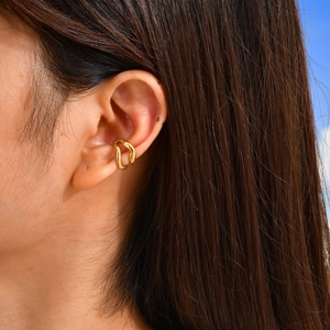 Gros plan d'un ear cuff doré à double vague porté sur le cartilage de l'oreille