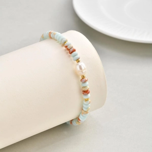 Detail of beaded bracelet with light blue beads, baroque pearl, and gold spacers
