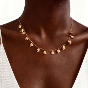 Detailansicht einer goldfarbenen Kette mit mehreren Kleeblatt-Anhängern an einem Modell