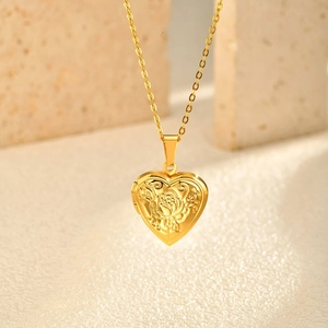 Golden heart locket pendant with embossed rose pattern on textured stone background
