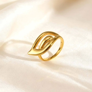 Close-up of golden hollow wing ring on silk fabric with polished 18K gold finish