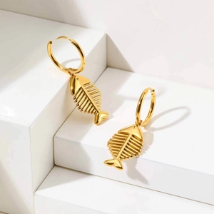 Detail view of gold fishbone hoop earrings displayed on white geometric props