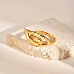 Macro shot of 18K gold plated hollow wing ring on natural textured stone background