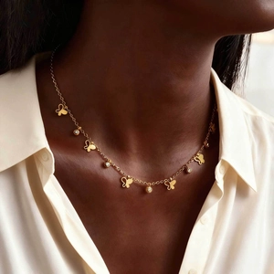 Goldene Schmetterlingskette mit Zirkonia-Anhängern an Model mit geometrischen Sternen