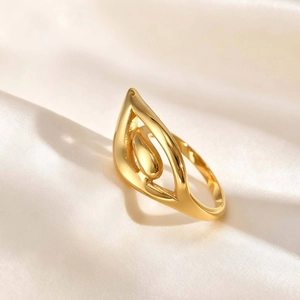 Detail of 18K gold teardrop wing ring on silk background with soft lighting focus