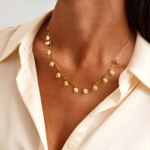 Elegante goldene Halskette mit Kleeblatt-Anhängern, am Hals eines Modells getragen