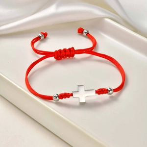 Detail of red braided rope bracelet with silver cross pendant and adjustable pull knot