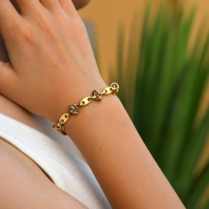 Dettaglio del bracciale dorato a maglia marina con nodi indossato sul polso