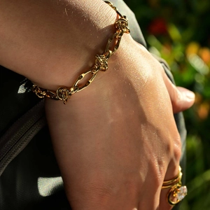 Primo piano del bracciale a maglie dorate e dell'anello indossati al polso femminile
