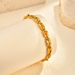 Macro-opname van een gouden schakelarmband op een witte stenen sokkel