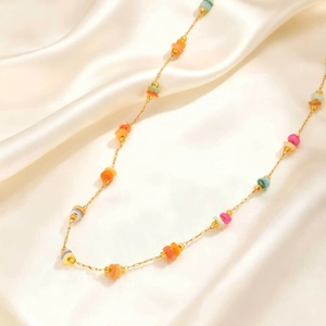 Gros plan d'un collier doré avec perles colorées sur un élégant tissu en soie beige