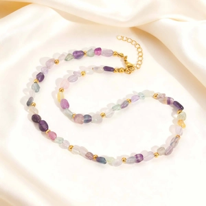 Detail of natural multicolor fluorite stone necklace with golden clasp on silk background