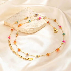 Gros plan d'une étiquette gravée 14K sur un collier de perles colorées dorées