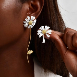 Détail de boucles d'oreilles marguerites asymétriques avec tiges dorées élégantes
