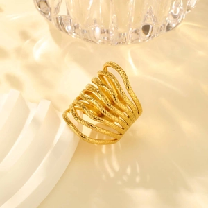 Detail of gold-plated wavy textured ring with embossed patterns on white display stand