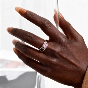 Detailed view of silver ring with pink zircon and geometric hollow setting on finger