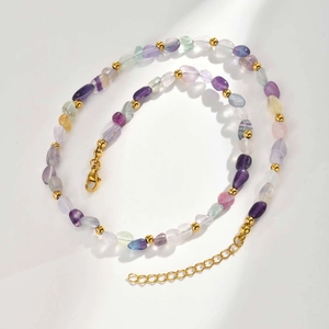Detailed macro view of colorful natural stone beads and gold spacers on a stainless steel chain