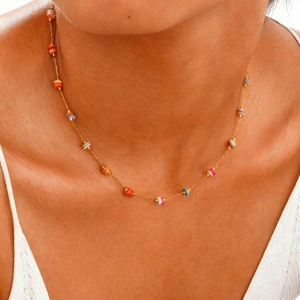 Détail d'un collier en acier doré avec des perles colorées porté sur le cou féminin