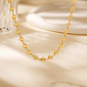 Dettaglio macro della collana a quadrifoglio dorata con finitura opaca spazzolata