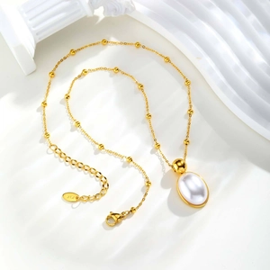 Detail of gold bead chain necklace with oval pearl pendant and K18 hallmark tag