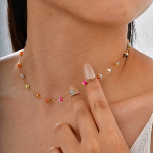 Gros plan d'un collier doré avec des perles colorées pour un style de plage d'été