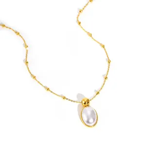 Close-up of golden necklace with oval pearl pendant and small gold bead accents
